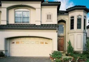 White paneled garage door with small windows across the top, in a large white stucco home.