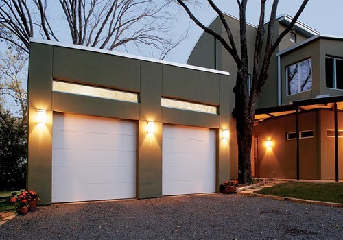 Two white garage doors in modern home with olive green siding.