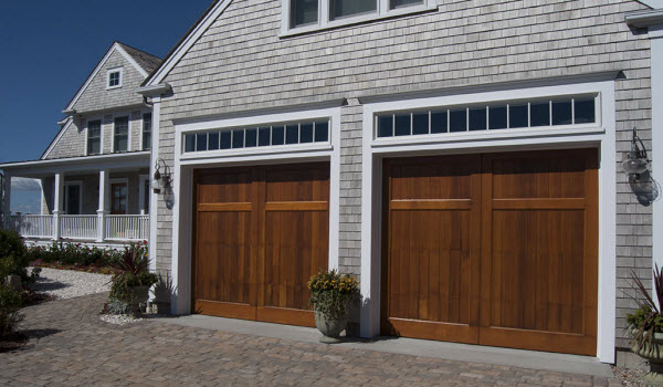 Carriage style wooden garage doors from Signature on a Cape Cod-style home with white-washed cedar shingle siding.